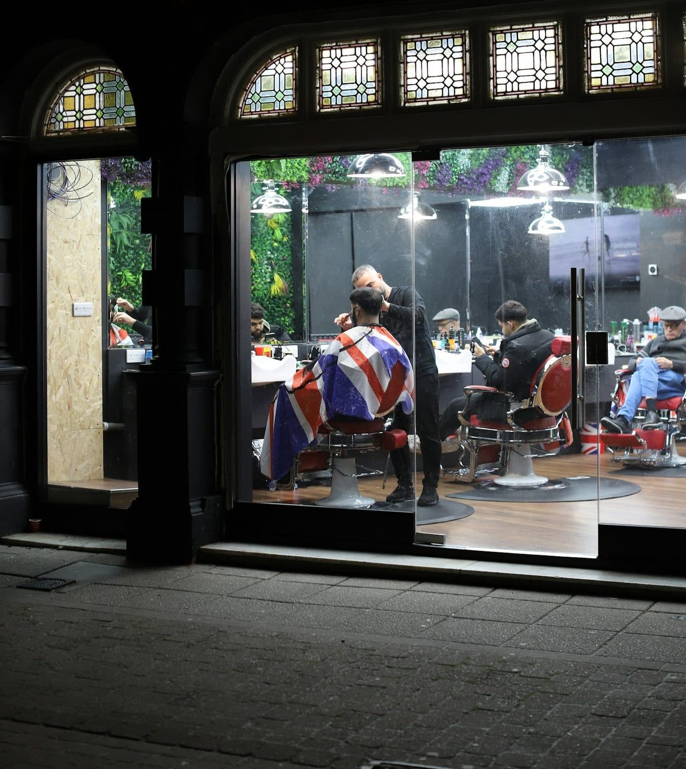A barbershop at night seen through its front window, chairs lit inside